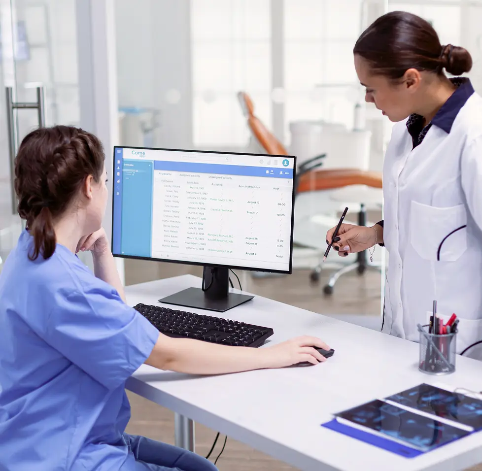 Two clinic staff reviewing patient appointments on a desktop screen